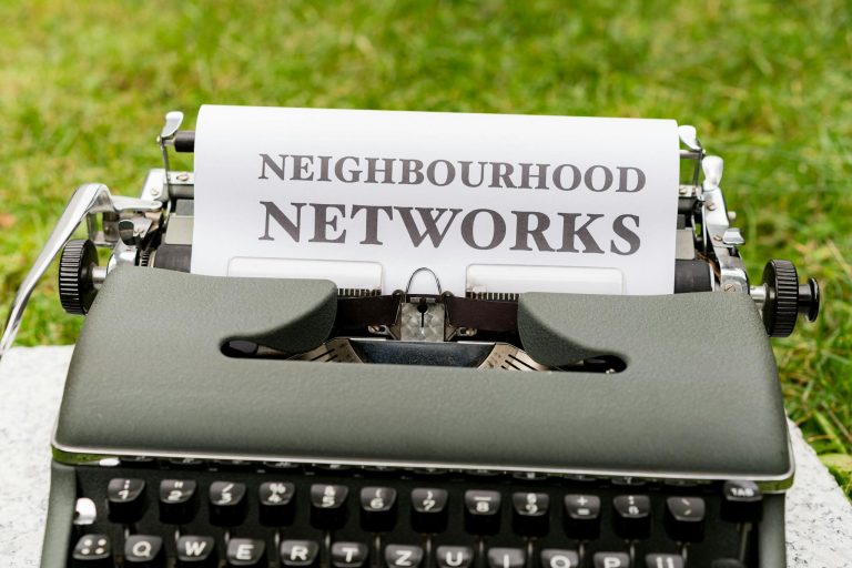 Retro typewriter displaying 'Neighborhood Networks' on paper, outdoors.
